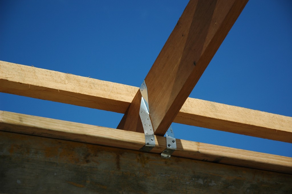 The trusses are tied down to the top plate of the wall with metal strap bracing