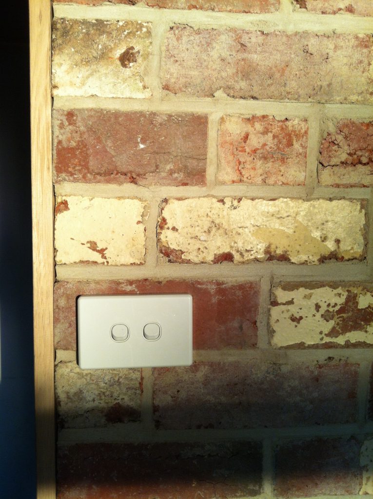 Rough and refined: the light switch installed on the recycled brick wall